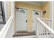 Close up of double front doors with welcome mat and outdoor lanterns, on a charming yellow townhome at 116 W 2Nd St, Folly Beach, SC 29439