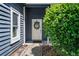 Front porch showcasing a white door with a wreath, dark blue siding, a manicured bush, and concrete walkway at 1414 E Crossing Ln, Mount Pleasant, SC 29466