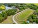Aerial view of a lake with a red roofed venue, a pond, an equestrian track, lush landscaping and mature trees at 1510 Old Rosebud Trl, Awendaw, SC 29429