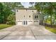 Exterior of home featuring four garage doors and a large concrete driveway surrounded by lush trees at 1510 Old Rosebud Trl, Awendaw, SC 29429