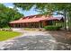 Stunning exterior shot of a large wooden event space with a red roof, set against a backdrop of lush trees and blue skies at 1510 Old Rosebud Trl, Awendaw, SC 29429