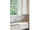Close up of a stainless steel kitchen faucet by a white farmhouse sink and patterned backsplash at 1510 Old Rosebud Trl, Awendaw, SC 29429