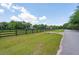 Sprawling acreage with black horse fencing, verdant pastures, and tree lined country road on a bright sunny day at 1510 Old Rosebud Trl, Awendaw, SC 29429
