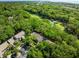 Aerial view showcasing homes surrounded by dense trees, with golf course visible and views of the water beyond at 153 High Hammock Villas, Seabrook Island, SC 29455