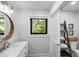 Bright bathroom features a marble vanity, wooden mirror, and a window view of lush greenery at 153 High Hammock Villas, Seabrook Island, SC 29455