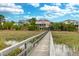 Scenic view of the home from the water, showcasing its beautiful setting near a wooden bridge at 2128 Breezy Point Dr, Mount Pleasant, SC 29466