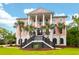 Stunning pink two-story home featuring a grand entrance, columns, and lush landscaping with palm trees at 2128 Breezy Point Dr, Mount Pleasant, SC 29466