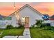 Charming white house featuring a unique peach-colored door, complemented by vibrant landscaping and soft string lights at 221 Trillium Ave, Summerville, SC 29483
