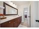 Bathroom features dark wood cabinets, white countertops, framed mirror, and a connecting doorway to another room at 3011 River Vista Way, Mount Pleasant, SC 29466
