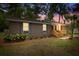 Beautiful brick home featuring new wooden porch with manicured lawn enhanced by landscape lighting at dusk at 411 Berkeley Dr, Moncks Corner, SC 29461