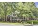Charming two-story home with red brick and white trim, featuring a welcoming front porch and lush landscaping at 4217 Meadowbrook Ct, North Charleston, SC 29420