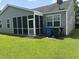 Home exterior featuring a screened in porch, lush lawn, and side utility containers at 4804 Oak Haven Pl, Summerville, SC 29485