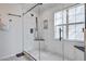Bright glass shower featuring white marbled tile, a black shower head, and a built in shower caddy at 486 Maple Oak Ln, Charleston, SC 29414