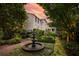 Spacious backyard featuring a tiered fountain, manicured hedges, and lush gardens under a colorful sunset sky at 5 Logan St, Charleston, SC 29401