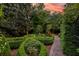 Manicured backyard showcasing meticulously shaped hedges, stone pathway, and lush greenery under an evening sky at 5 Logan St, Charleston, SC 29401