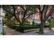 Two-story house showcasing a manicured front yard with mature trees and an iron fence with gated entry at 5 Logan St, Charleston, SC 29401