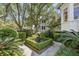 Lush garden with manicured hedges, mature trees, and a decorative urn at 5 Logan St, Charleston, SC 29401