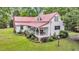 Exterior view of a charming home with a red roof, a welcoming porch, and well-maintained landscaping at 516 Hope Plantation Ln, Jacksonboro, SC 29452