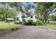 Exterior of a cozy home with a gravel driveway, mature trees, and a rustic storage shed at 516 Hope Plantation Ln, Jacksonboro, SC 29452