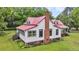 Exterior home view showcasing red roof, with a side entrance, surrounded by verdant greenery at 516 Hope Plantation Ln, Jacksonboro, SC 29452