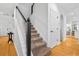 Carpeted staircase with white risers and black accent newel post adjacent to the entry and hardwood floors at 555 Pointe Of Oaks Rd, Summerville, SC 29485