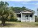 Exterior view of a white one-story home with a porch, in need of renovation at 650 Atlantic St, Mount Pleasant, SC 29464