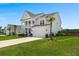 Charming two-story home with a front porch, attached garage, lush landscaping, and blue sky at 682 Pontoon Rd, Huger, SC 29450
