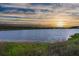 A beautiful lake with a sunset view in the distance and green grass in the foreground at 682 Pontoon Rd, Huger, SC 29450