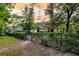 Fenced backyard featuring mature trees and landscaping, with a gate leading to the garden at 8662 W Fairway Woods Dr, North Charleston, SC 29420
