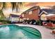 Beautiful backyard pool surrounded by lounge furniture and lush landscaping with rear elevation at dusk at 8662 W Fairway Woods Dr, North Charleston, SC 29420