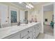 Bright bathroom featuring a double sink vanity with a marble countertop, white cabinets, and large mirror at 8662 W Fairway Woods Dr, North Charleston, SC 29420