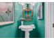 Stylish powder room with a pedestal sink, decorative mirror, and teal walls at 8662 W Fairway Woods Dr, North Charleston, SC 29420