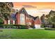 Beautiful two-story brick home with manicured lawn, mature trees and two-car garage at dusk at 8662 W Fairway Woods Dr, North Charleston, SC 29420