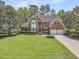 Beautiful brick home with a well-manicured lawn, mature trees, and a two-car garage at 8662 W Fairway Woods Dr, North Charleston, SC 29420