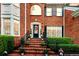 Charming brick front porch with decorative wreath, topiaries, and brick stairs with black metal railing at 8662 W Fairway Woods Dr, North Charleston, SC 29420