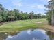 Picturesque view of a golf course with a sand trap and pond reflecting a tranquil sky at 8662 W Fairway Woods Dr, North Charleston, SC 29420