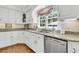 Bright kitchen featuring white cabinets, a stainless steel dishwasher, and a sunny window at 8662 W Fairway Woods Dr, North Charleston, SC 29420