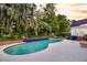 Beautiful backyard pool surrounded by lush landscaping and palm trees with a view of rear elevation at 8662 W Fairway Woods Dr, North Charleston, SC 29420