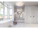 A modern bathroom featuring double doors, marble floors, a soaking tub and a large framed mirror above the vanity at 952 Mccants Dr, Mount Pleasant, SC 29464