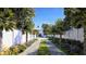 A long paver driveway lined with palm trees and flowers leading to a traditional home with a white fence at 952 Mccants Dr, Mount Pleasant, SC 29464
