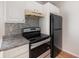 Galley style kitchen featuring black appliances, granite counters and gray tile backsplash at 111 Elmwood Ave # A, Ladson, SC 29456