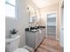 Well-lit bathroom featuring a double vanity, gray cabinetry, wood-look floors, and a door opening into a walk-in closet at 1224 Midvale Ave, Charleston, SC 29412