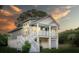 Beautiful elevated home with a front porch, white stairs, and a garage underneath at 1224 Midvale Ave, Charleston, SC 29412