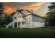 Beautiful raised home with a charming design, showcasing the porch and yard with a picturesque sunset backdrop at 1224 Midvale Ave, Charleston, SC 29412