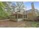 View of the backyard showcasing a covered porch, chimney, and foliage-covered lawn at 123 Lewisfield Dr, North Charleston, SC 29418