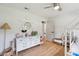 Well-lit bedroom featuring light wood floors, and a white dresser with decorative mirror at 1467 Battalion Dr, James Island, SC 29412