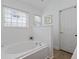 A clean white bathroom with a soaking tub, window, and white tiled wall at 1525 Cypress Pointe Dr, Mount Pleasant, SC 29466