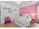 A charming bedroom with a pink accent wall, modern chandelier, and window at 1525 Cypress Pointe Dr, Mount Pleasant, SC 29466