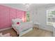 A charming bedroom with a pink accent wall, modern chandelier, and window at 1525 Cypress Pointe Dr, Mount Pleasant, SC 29466