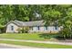 Inviting single-story brick home displaying light blue shutters, surrounded by lush, mature trees and manicured front lawn at 1673 Sulgrave Rd, Charleston, SC 29414